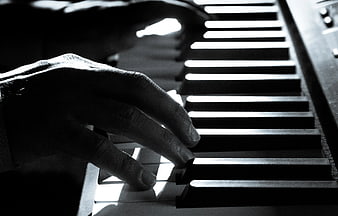 Close-up of hands playing piano keys in black and white
