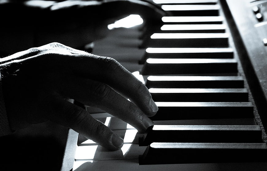 Close-up of hands playing piano keys in black and white