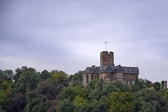 Historic stone castle on a lush green hill under cloudy sky