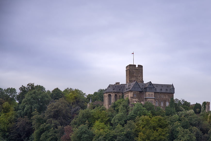 Historic stone castle on a lush green hill under cloudy sky