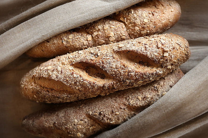 Freshly baked whole wheat bread loaves on linen cloth