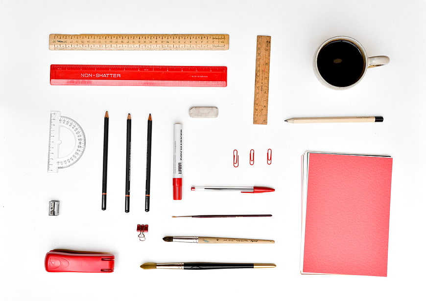 Flat lay of red and black stationery with coffee on white background