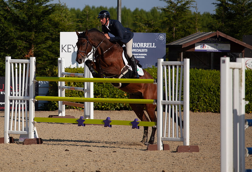 Equestrian horse jumping over obstacle in competition