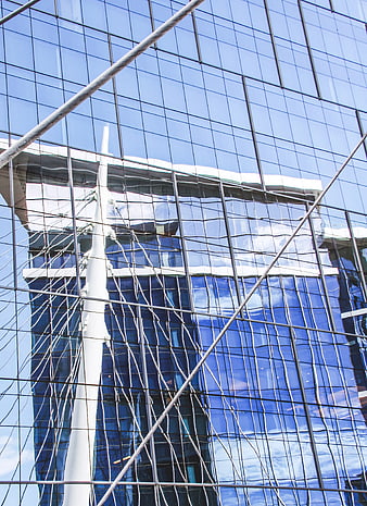 Modern glass building facade with sky reflection
