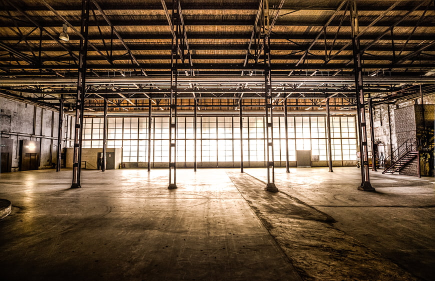 Empty industrial warehouse interior with large windows and steel beams