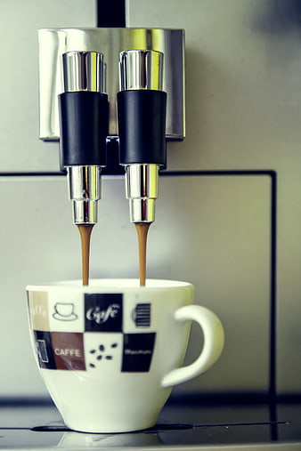 Espresso pouring from dual spouts into a white ceramic cup
