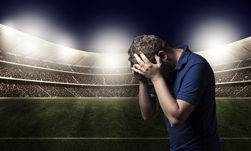 Disappointed football player holding head in stadium