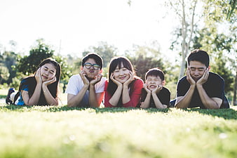 Happy Asian Family Lying on Grass in Park