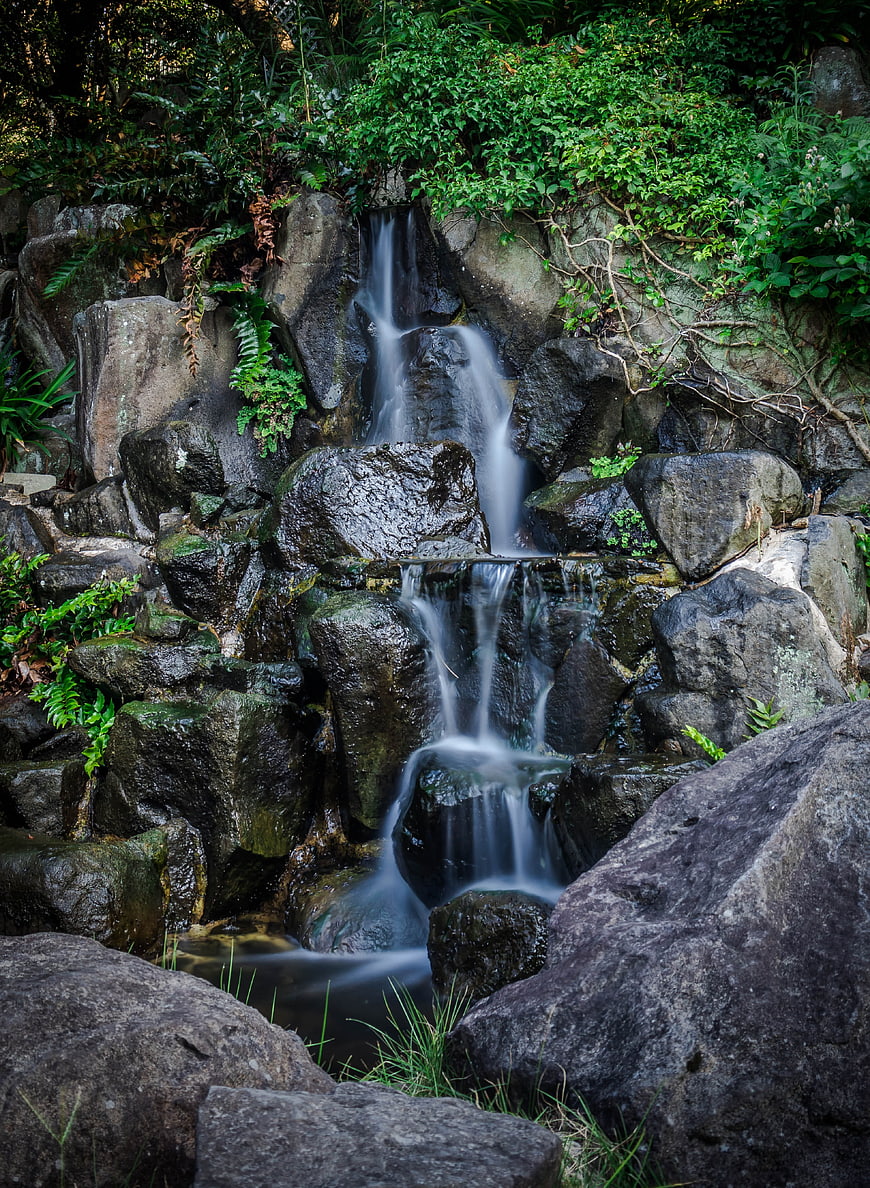 Small Waterfall Cascading Over Rocks In Lush Green Forest