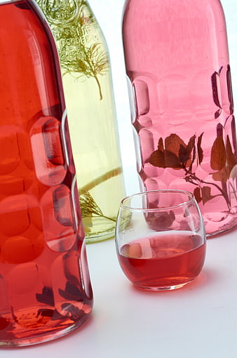 Colorful Infused Bottles with Herbs and Red Drink