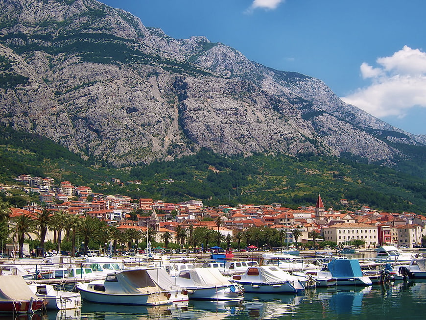 Boats in harbor with coastal town and mountains