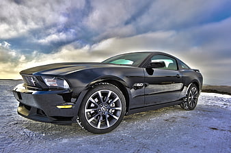 Black Ford Mustang GT on Snowy Road Under Dramatic Sky