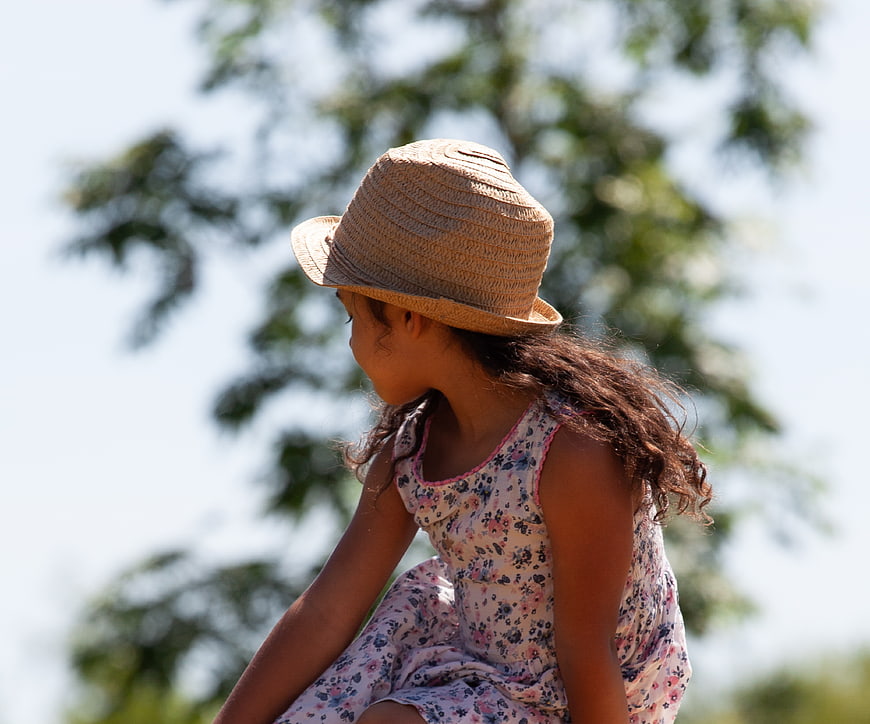 Young girl in straw hat and floral dress looking away