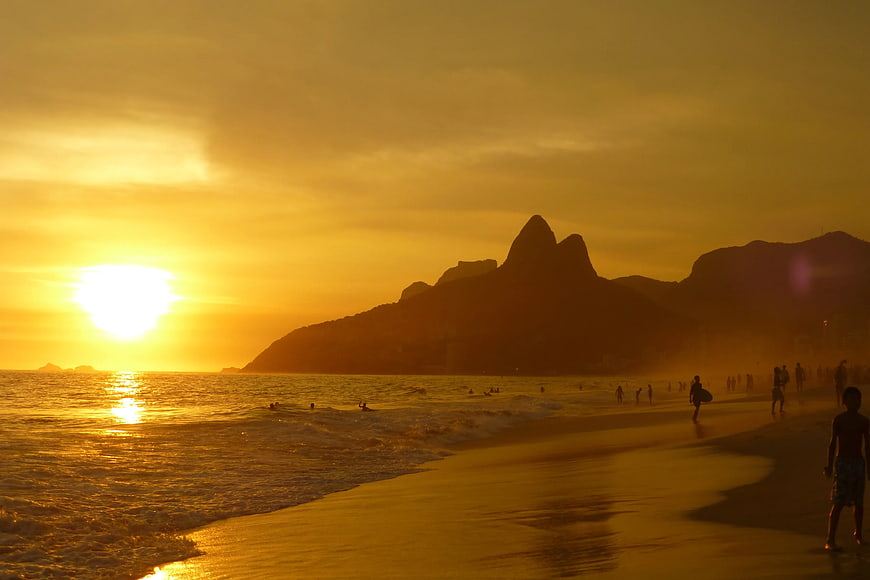 Silhouetted Beach Sunset with Mountains and People