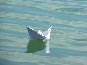 Origami paper boat floating on calm water