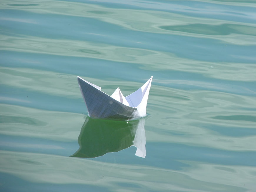 Origami paper boat floating on calm water