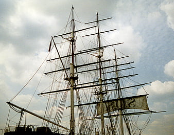 Historic sailing ship masts and rigging against cloudy sky