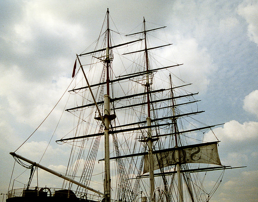 Historic sailing ship masts and rigging against cloudy sky