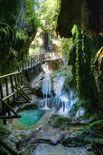 Lush waterfall cascading into turquoise pool with wooden walkway