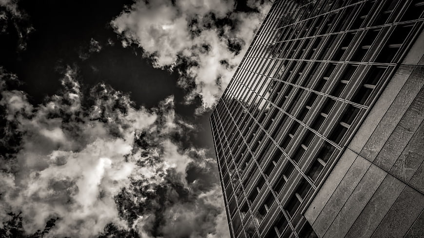Black and white skyscraper against dramatic cloudy sky