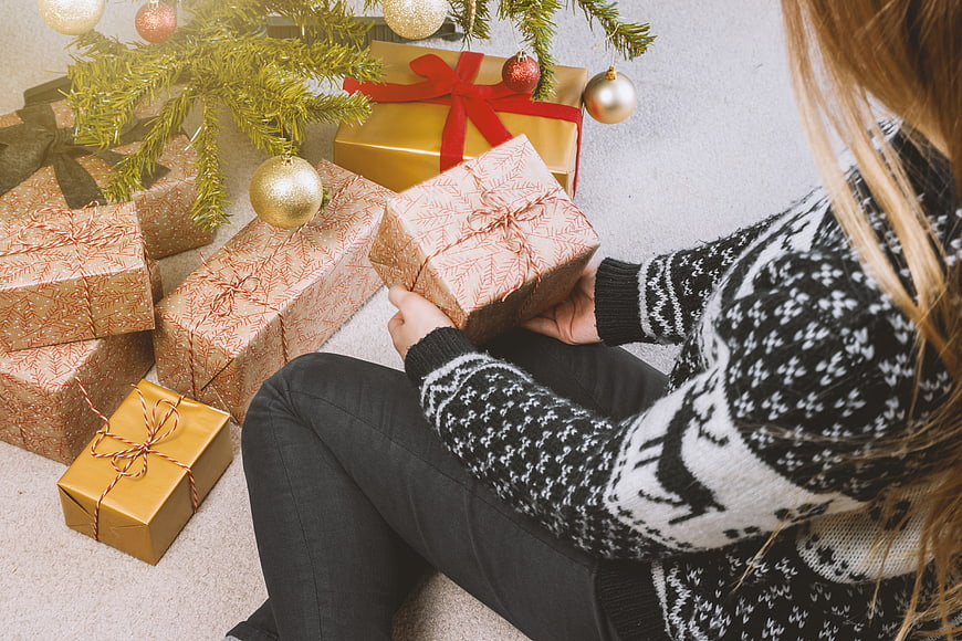 Woman Wrapping Christmas Gifts Under Tree