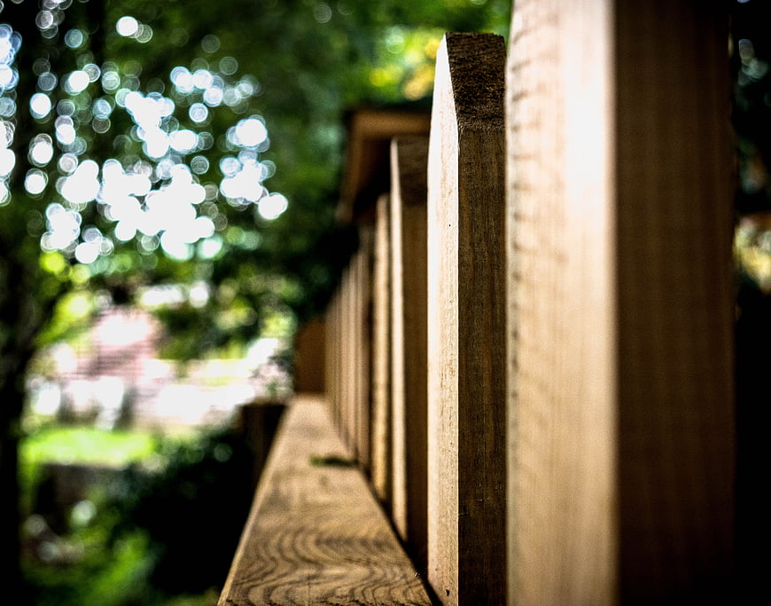 Close-up of wooden fence with blurred green forest background