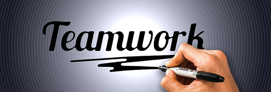 Hand writing the word Teamwork with a marker on a conceptual background