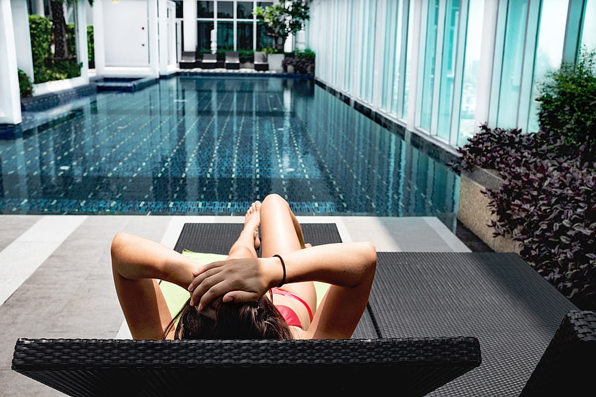 Woman relaxing on lounge chair by infinity pool