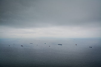 Aerial view of cargo ships on calm ocean under overcast sky
