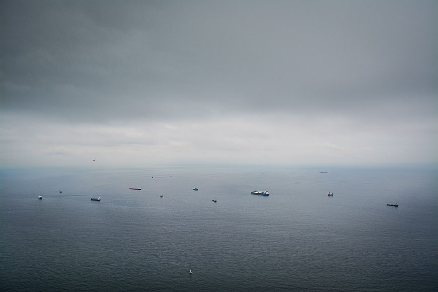Aerial view of cargo ships on calm ocean under overcast sky