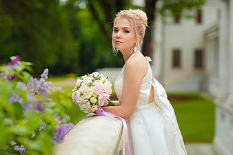 Bride in White Wedding Dress Holding Bouquet in Garden