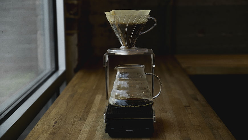 Pour-over coffee brewing on wooden table by window