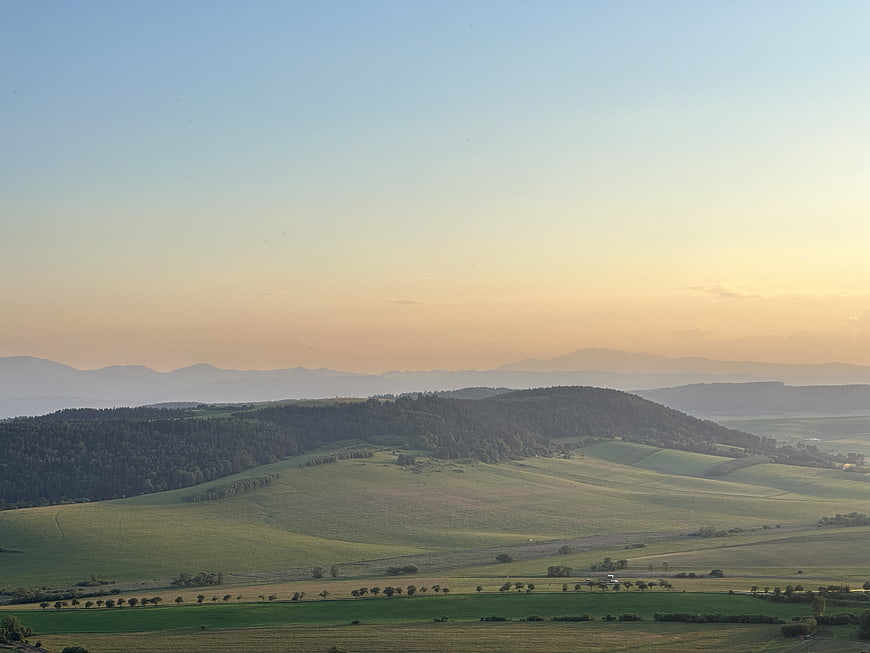 Serene Rolling Hills Landscape at Golden Hour with Distant Mountains