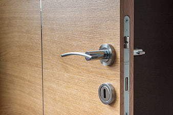 Close-up of modern wooden door with chrome handle and lock