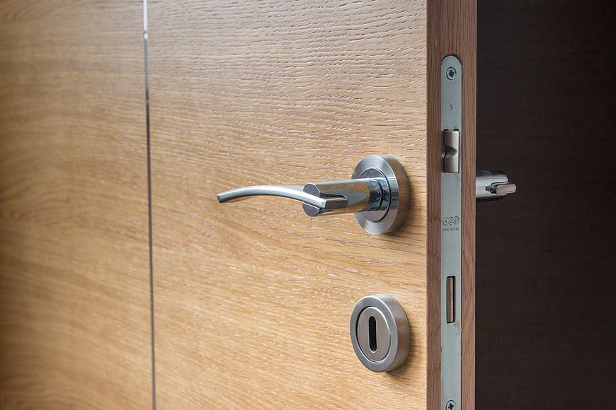 Close-up of modern wooden door with chrome handle and lock