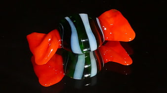 Colorful glass candy sculpture on black reflective surface