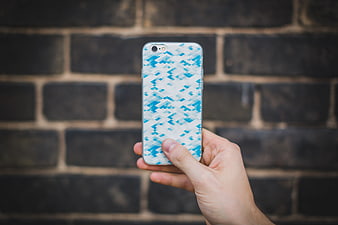 Hand holding smartphone with blue geometric pattern case