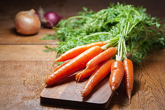 Fresh Carrots with Greens on Wooden Cutting Board