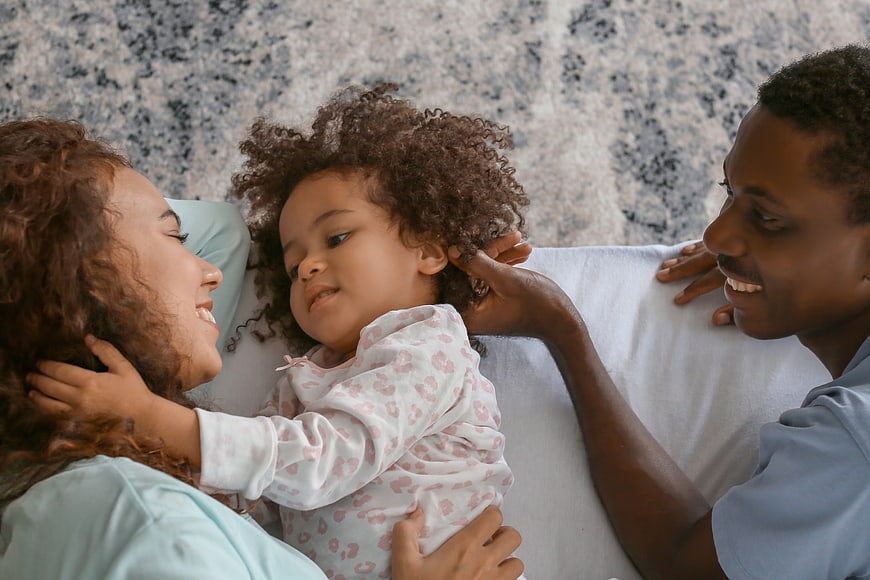Happy African American Family Lying on Bed Together