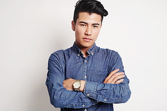 Confident young Asian man in denim shirt with arms crossed