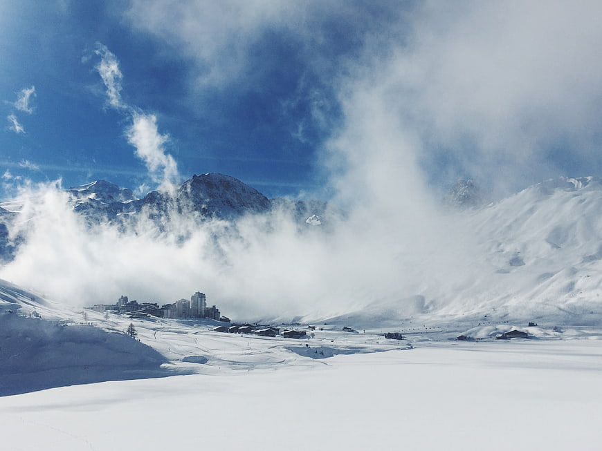 Snowy mountain landscape with clouds and ski resort buildings