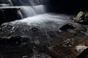 Flowing waterfall cascading over dark rocks in a stream