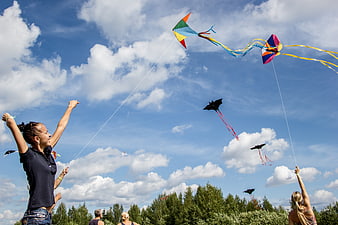 People Flying Colorful Kites In Blue Sky