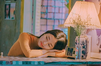 Melancholic young woman resting head on table in warm indoor setting