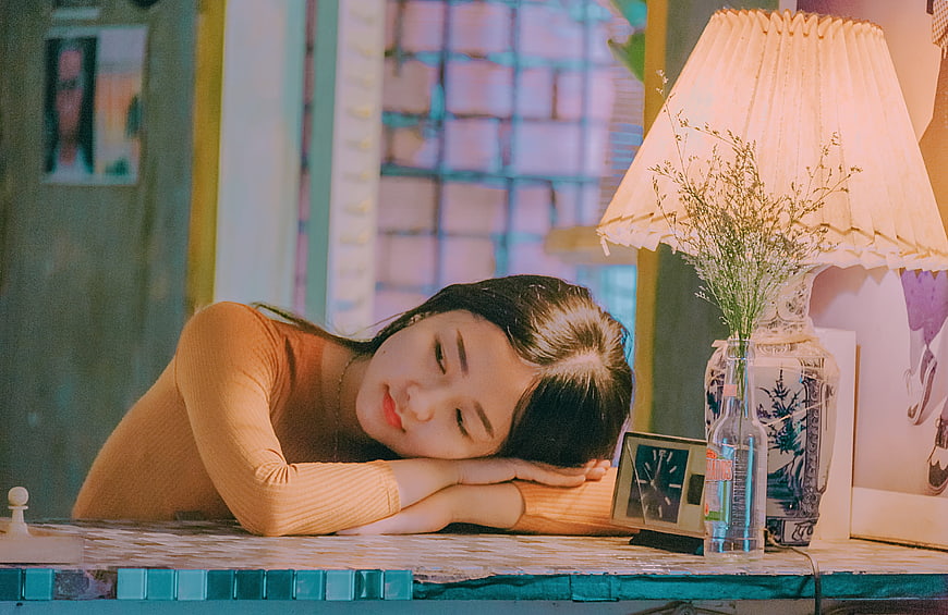 Melancholic young woman resting head on table in warm indoor setting