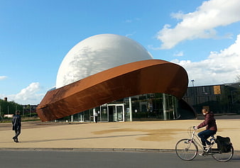 Modern Science Center with Rust-Colored Roof and Cyclist