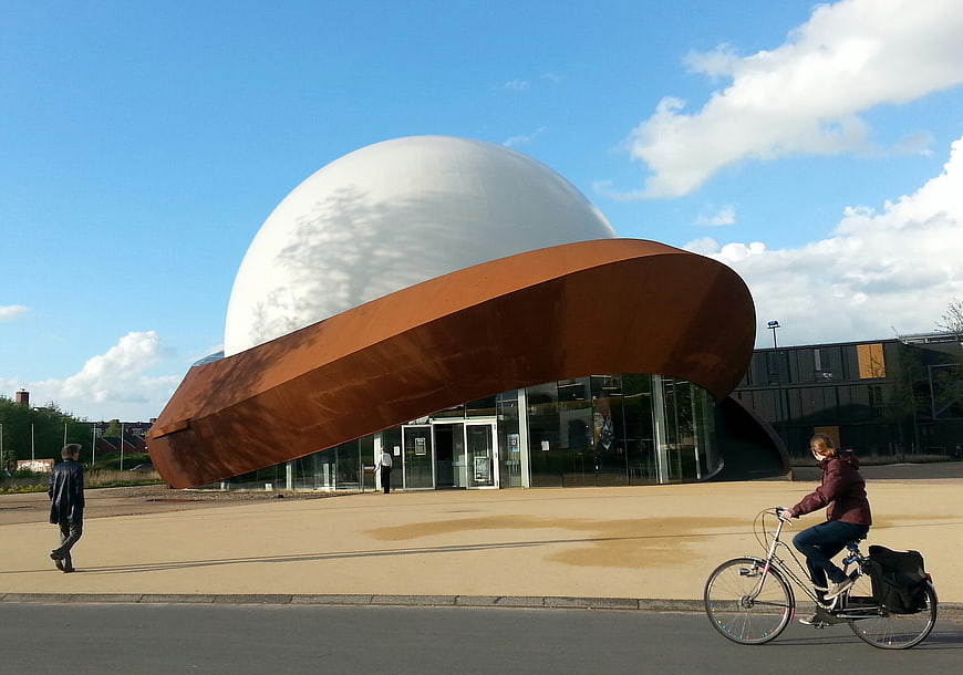 Modern Science Center with Rust-Colored Roof and Cyclist