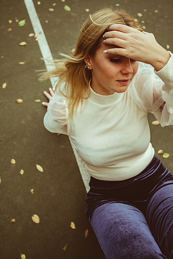 High angle portrait of woman sitting on pavement in autumn