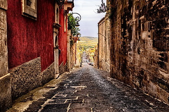 Historic Cobblestone Alleyway in Sicily, Italy with Red Building Facade