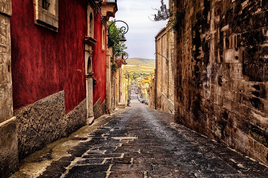 Historic Cobblestone Alleyway in Sicily, Italy with Red Building Facade